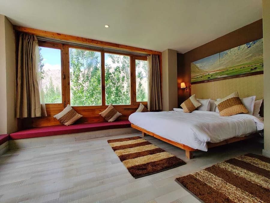 Un dormitorio con una cama grande, un banco con cojines y un cuadro en la pared.