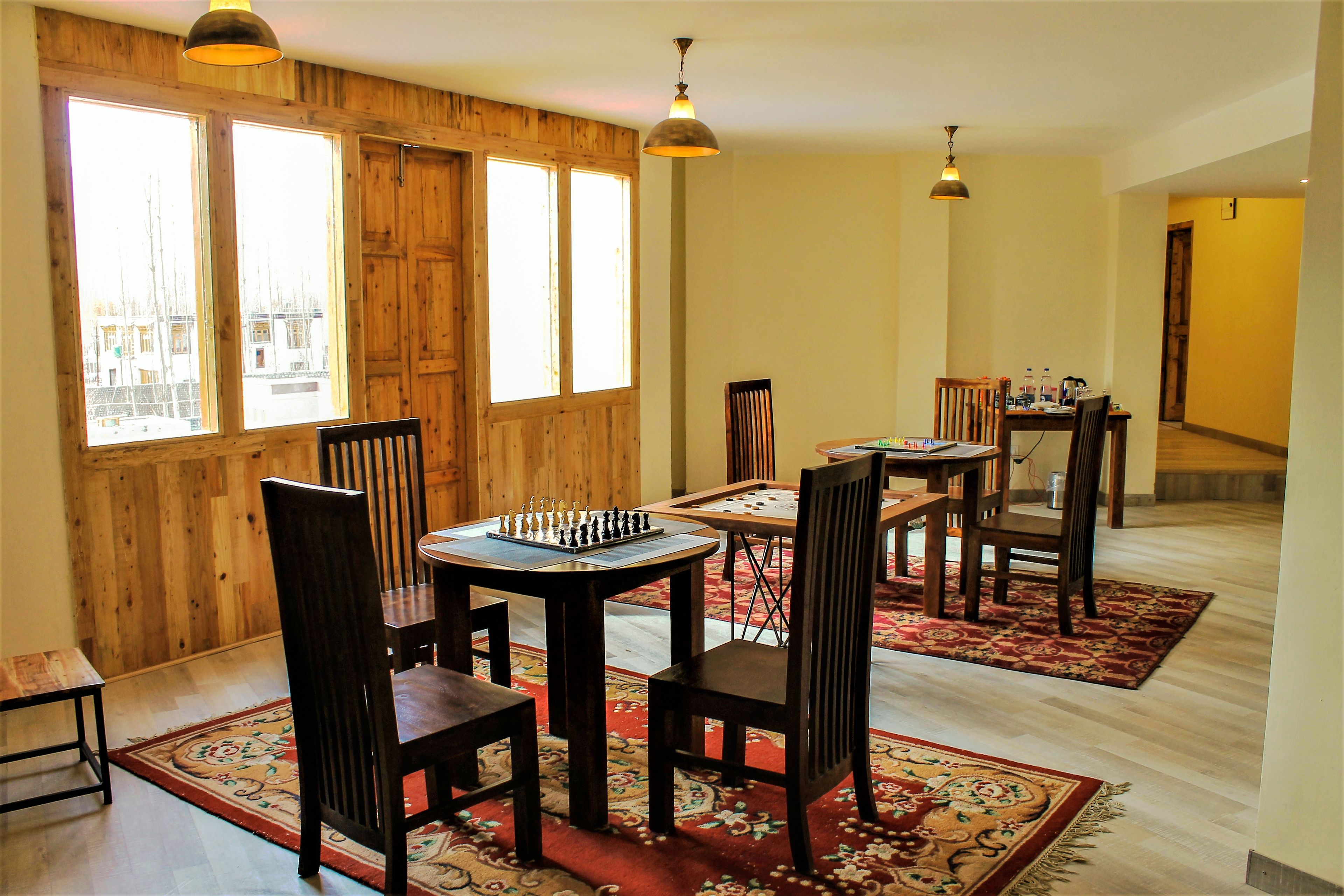 A dining area with wooden walls, large windows, and a chessboard on the table.