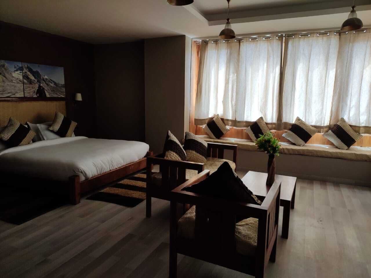 Een kamer met een bed, een bank, een eettafel en een raam met gordijnen.