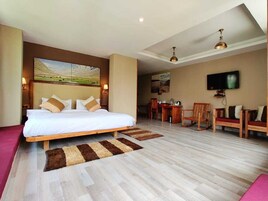 A bedroom with a large bed, a desk, and a TV.