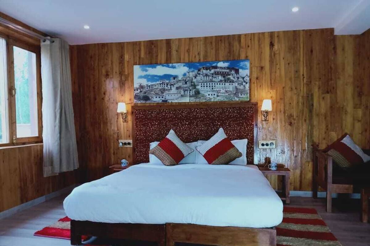 A wooden-paneled bedroom with a large bed, two bedside lamps, and a painting above the bed.