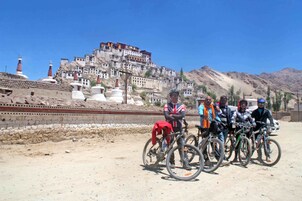 Un grupo de personas con bicicletas frente a un complejo monástico histórico.