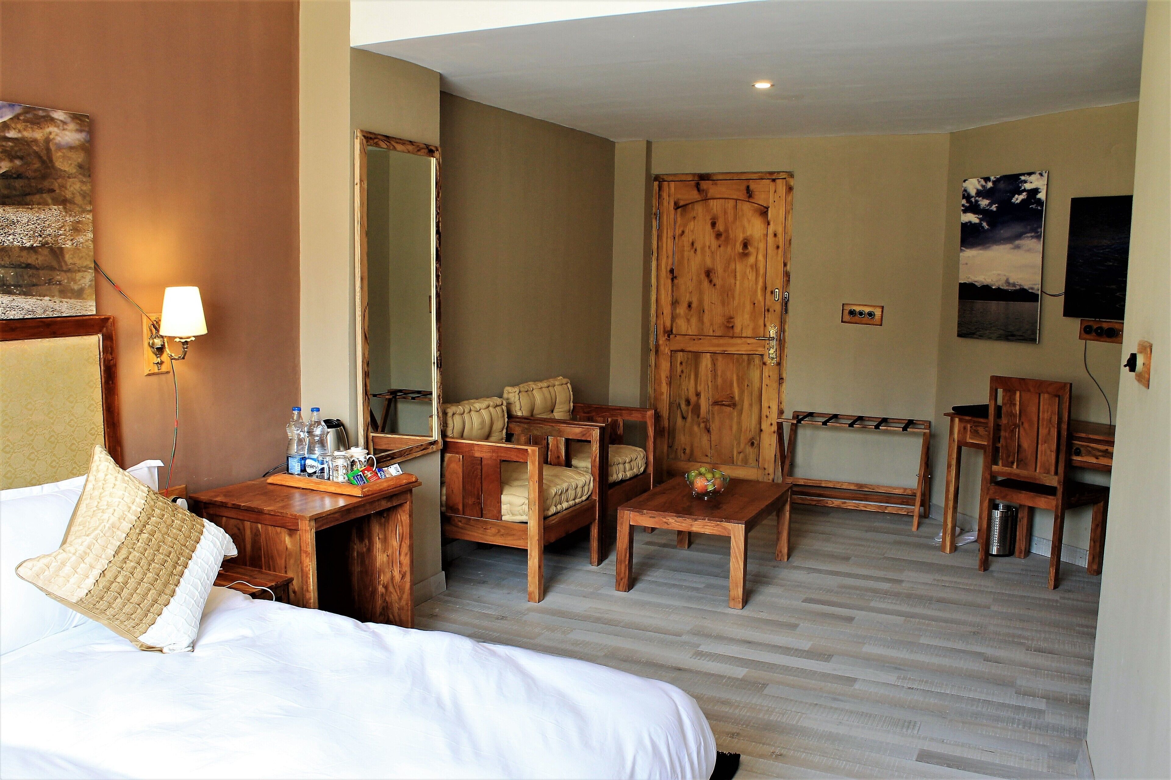 Ein Hotelzimmer mit einem Bett, einem Holzschrank, zwei Holzstühlen, einem kleinen Holztisch und einem Schreibtisch mit Stuhl.
