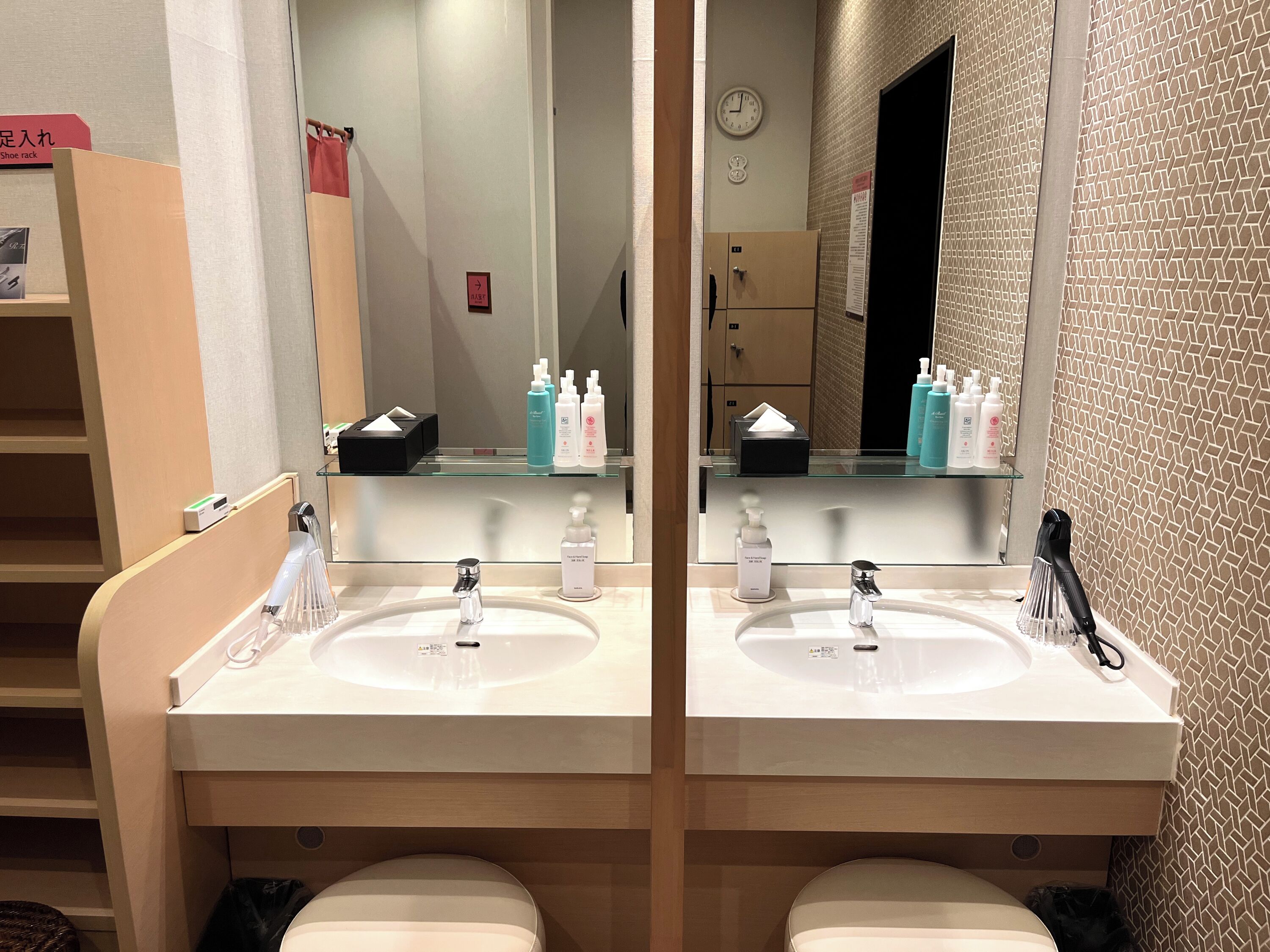 A bathroom with two sinks, a mirror, and a clock on the wall.