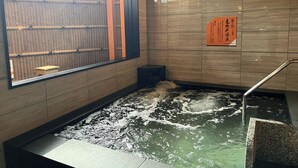 A hot spring area with a wooden wall, a small table, and a sign in Japanese. - APA Hotel Joetsu Myoko Ekimae (Joetsu)