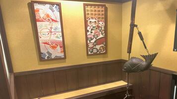 A restaurant interior with wooden paneling, a fish-shaped hanging light, and two decorative panels with Asian motifs.