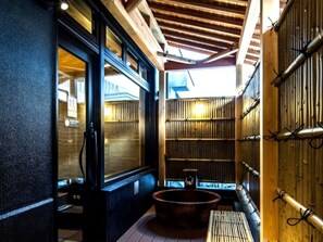 Ett traditionellt japanskt rum med tatamimattor på golvet, ett träpanelat tak och en vägg av bambuskärmar.