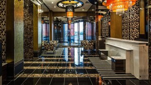 A modern hotel lobby with a reflective black and gold floor, a central chandelier, and patterned walls. - APA Hotel Joetsu Myoko Ekimae (Joetsu)