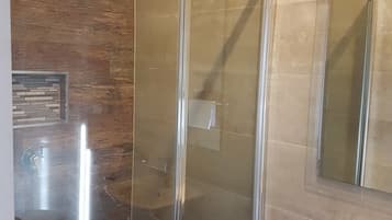 Un bagno con cabina doccia in vetro, lavandino e specchio.