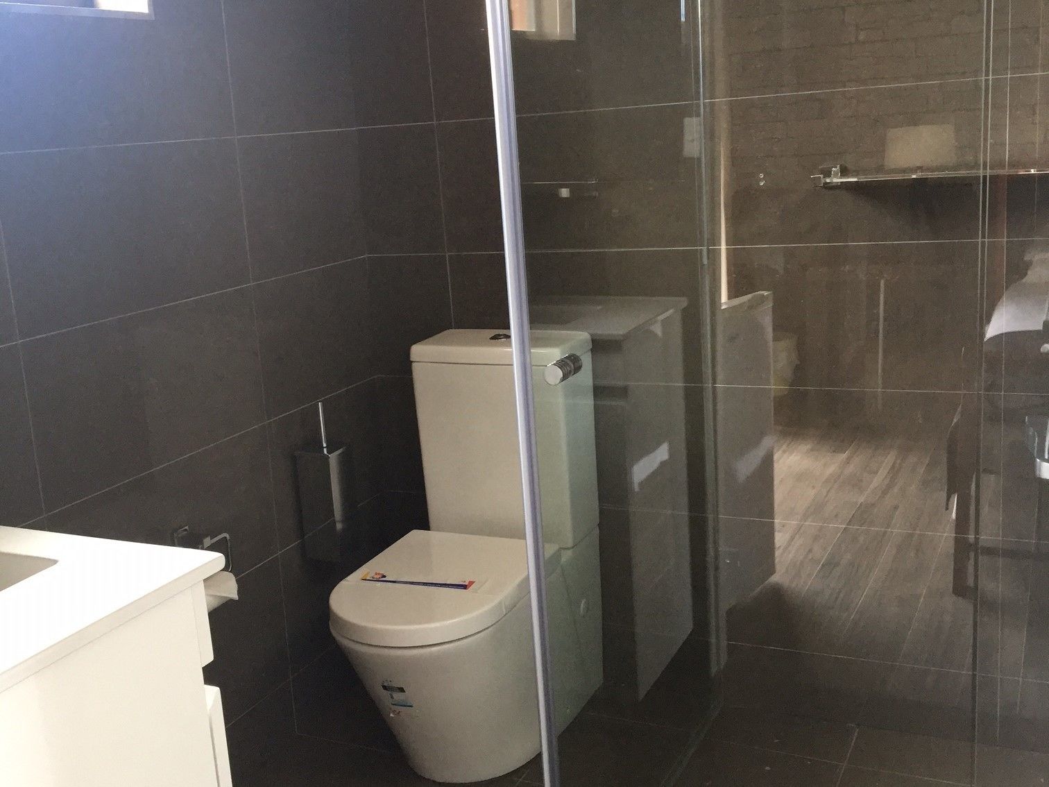 A bathroom with a toilet, a sink, and a glass shower enclosure.