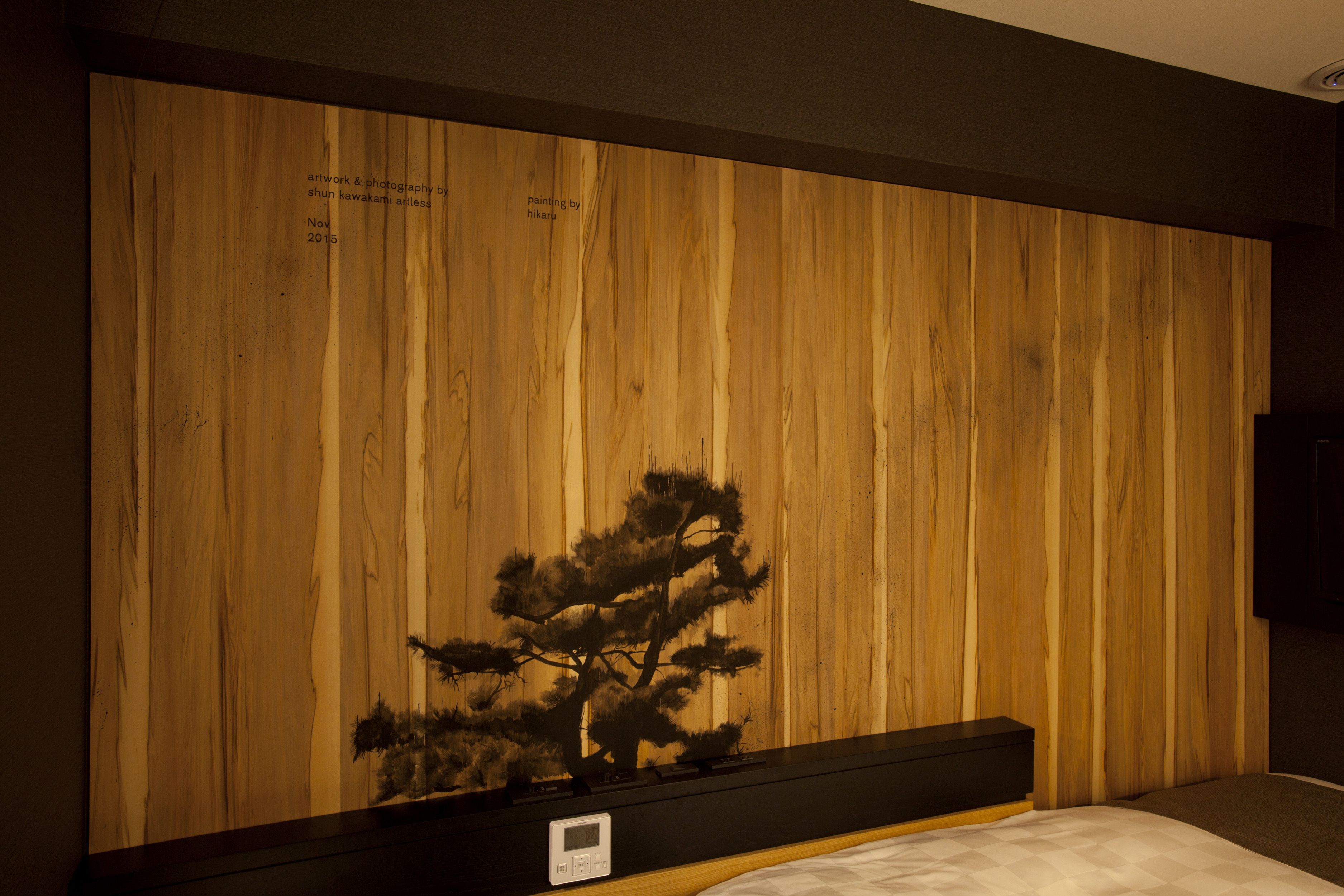 A bedroom with a wooden wall, a bed, and a small table with a clock.