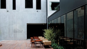 Exterior moderno de un hotel con un área de estar al aire libre cubierta, un letrero que dice 'HOTEL RISVEGLIO AKASAKA' y fachada de vidrio.
