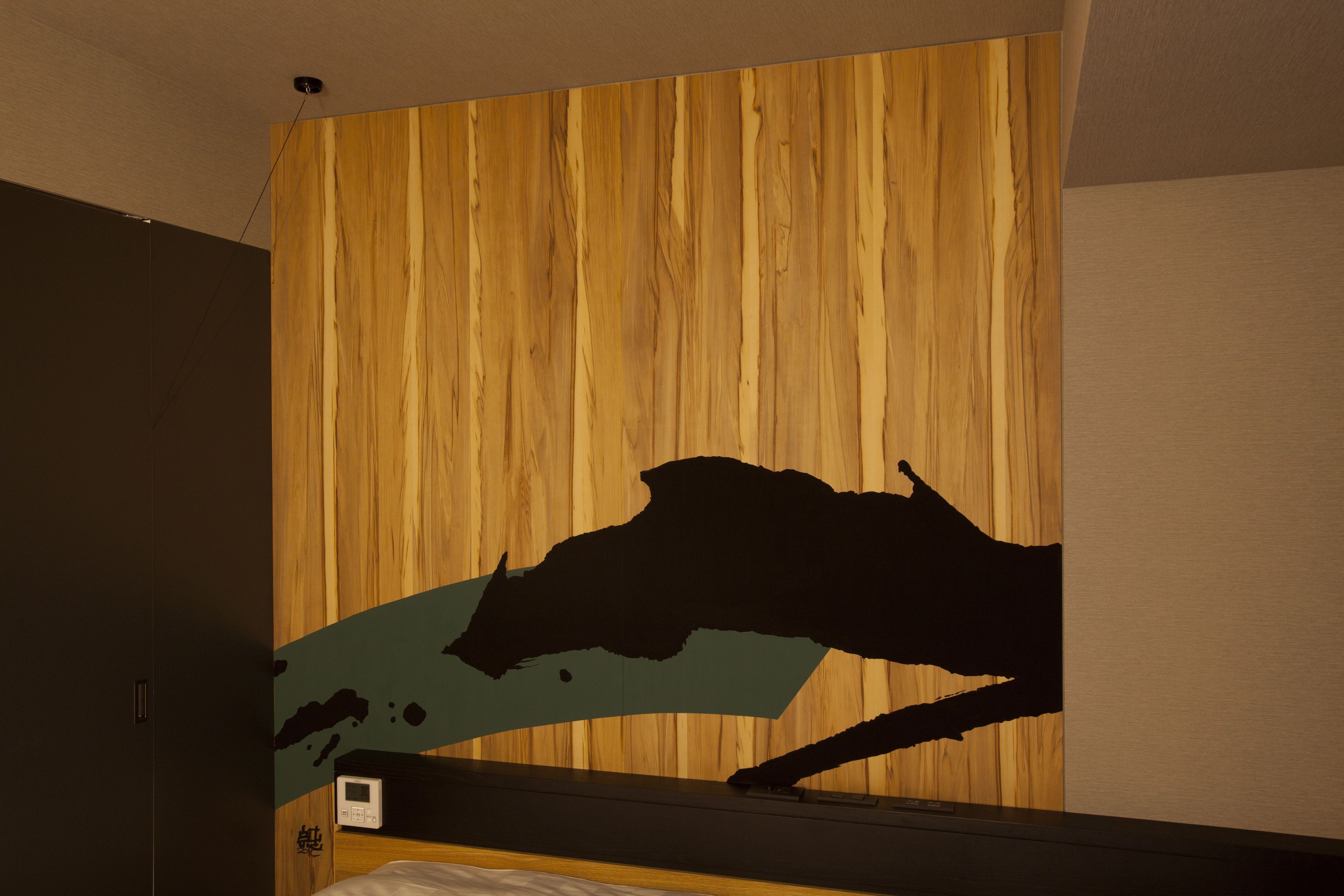 A room with a wooden wall and a bed with a black headboard.