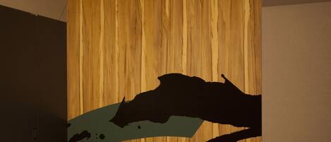 A room with a wooden wall and a bed with a black headboard.