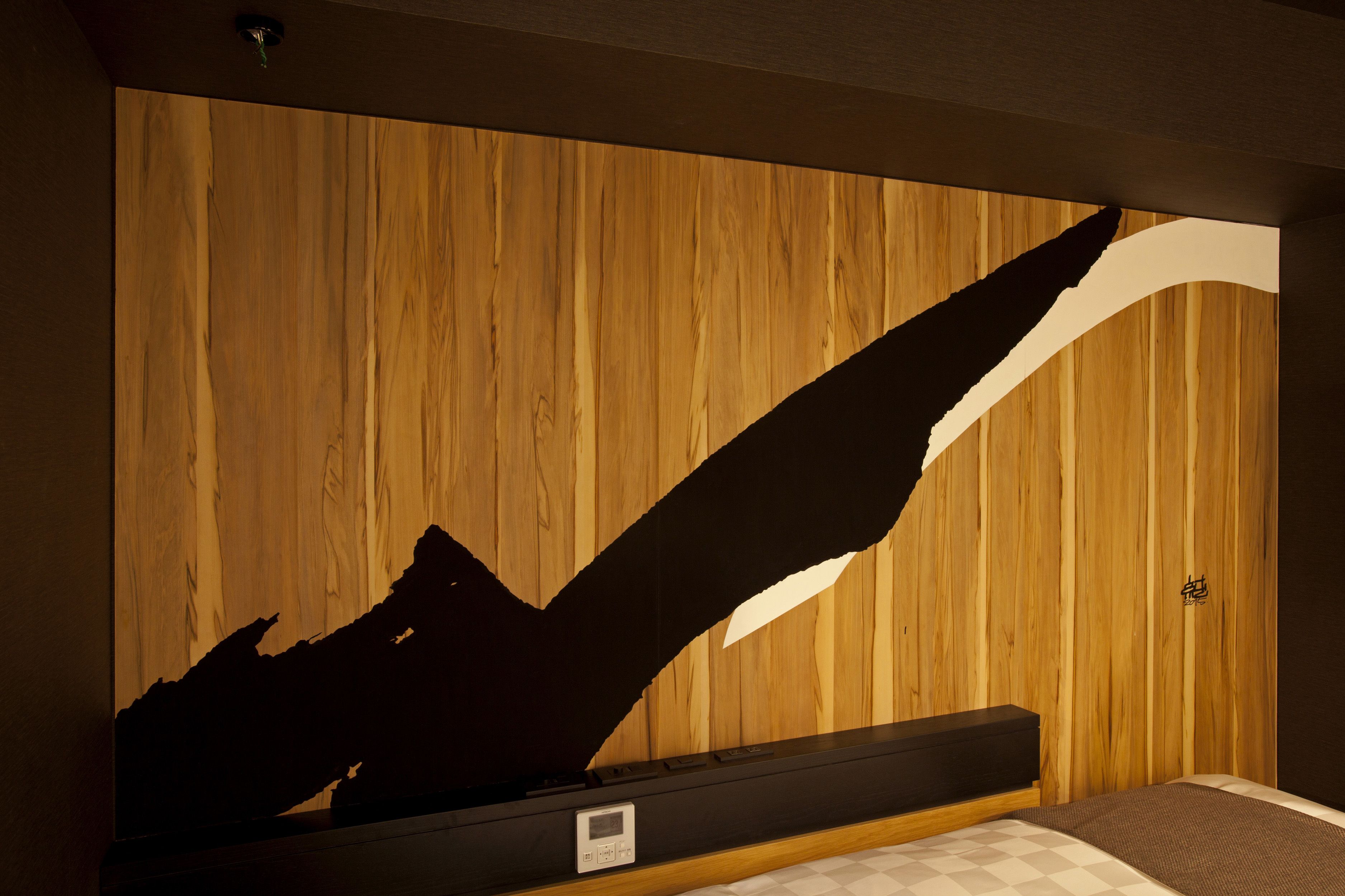 Une chambre avec un mur en bois, un lit et une grande sculpture abstraite.