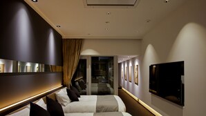 Habitación de hotel con dos camas, un espejo grande, un televisor de pantalla plana y un pasillo que conduce a otra habitación.