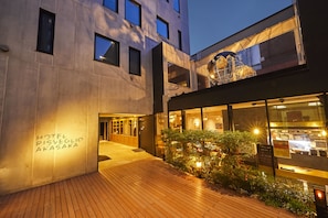 Exterior moderno de un hotel con terraza de madera, entrada de vidrio y un letrero que dice "HOTEL RISVEGLIO AKASAKA".