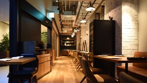 A modern restaurant with wooden tables and chairs, a brick wall, and pendant lighting. - Hotel Risveglio Akasaka (Tokyo)