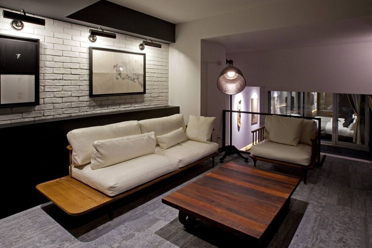 A modern living room with a white brick wall, two sofas, a wooden coffee table, and a pendant light.