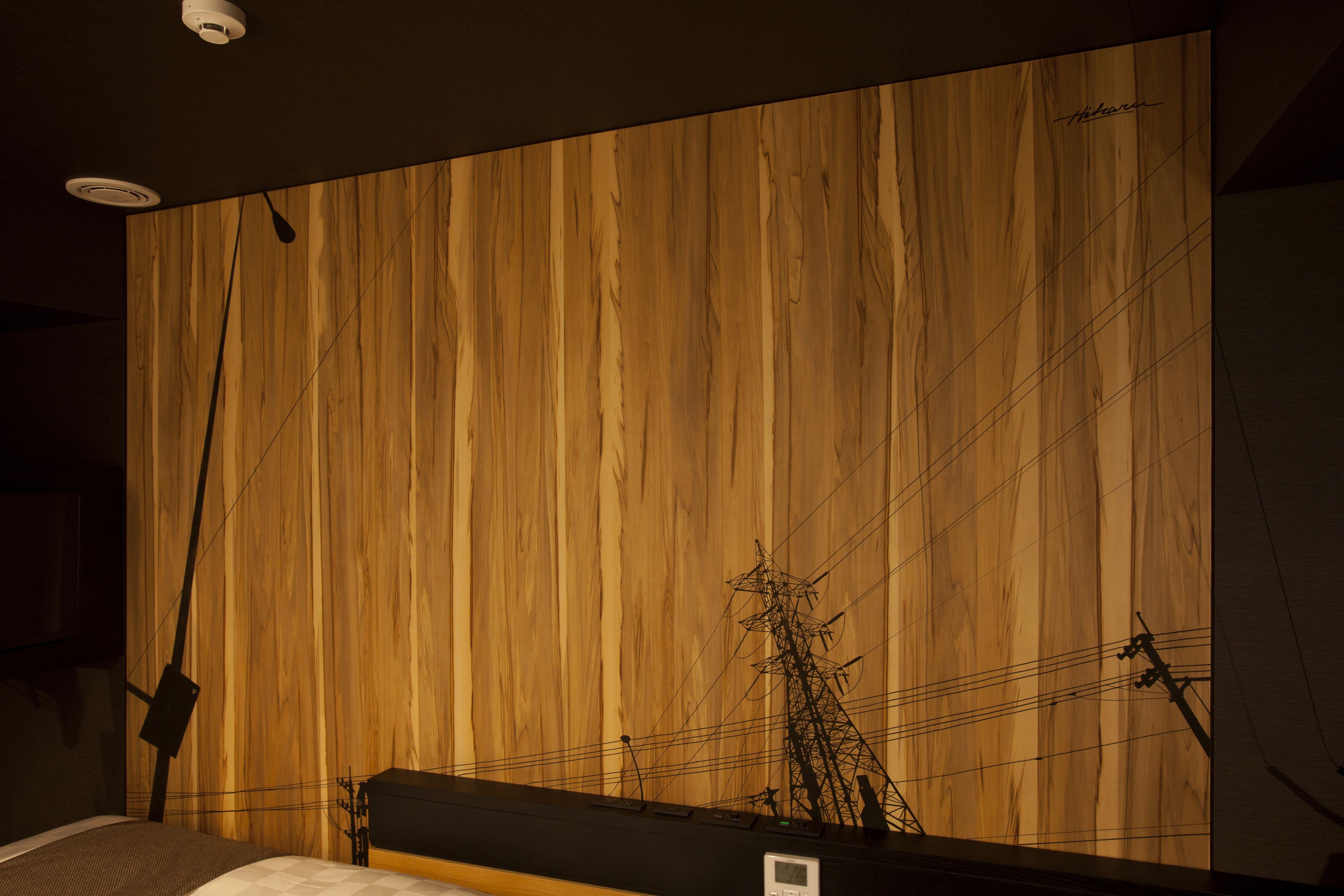 A room with a wooden wall, a bed, and a ceiling light.