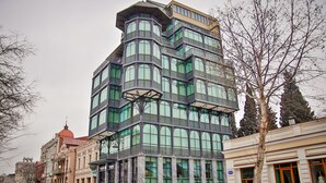 A multi-story building with a distinctive corner design, large windows, and a green facade. - New Tiflis Hotel (Tbilisi)