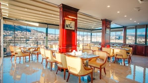 A spacious restaurant with high ceilings, large windows offering city views, and polished floors. - New Tiflis Hotel (Tbilisi)