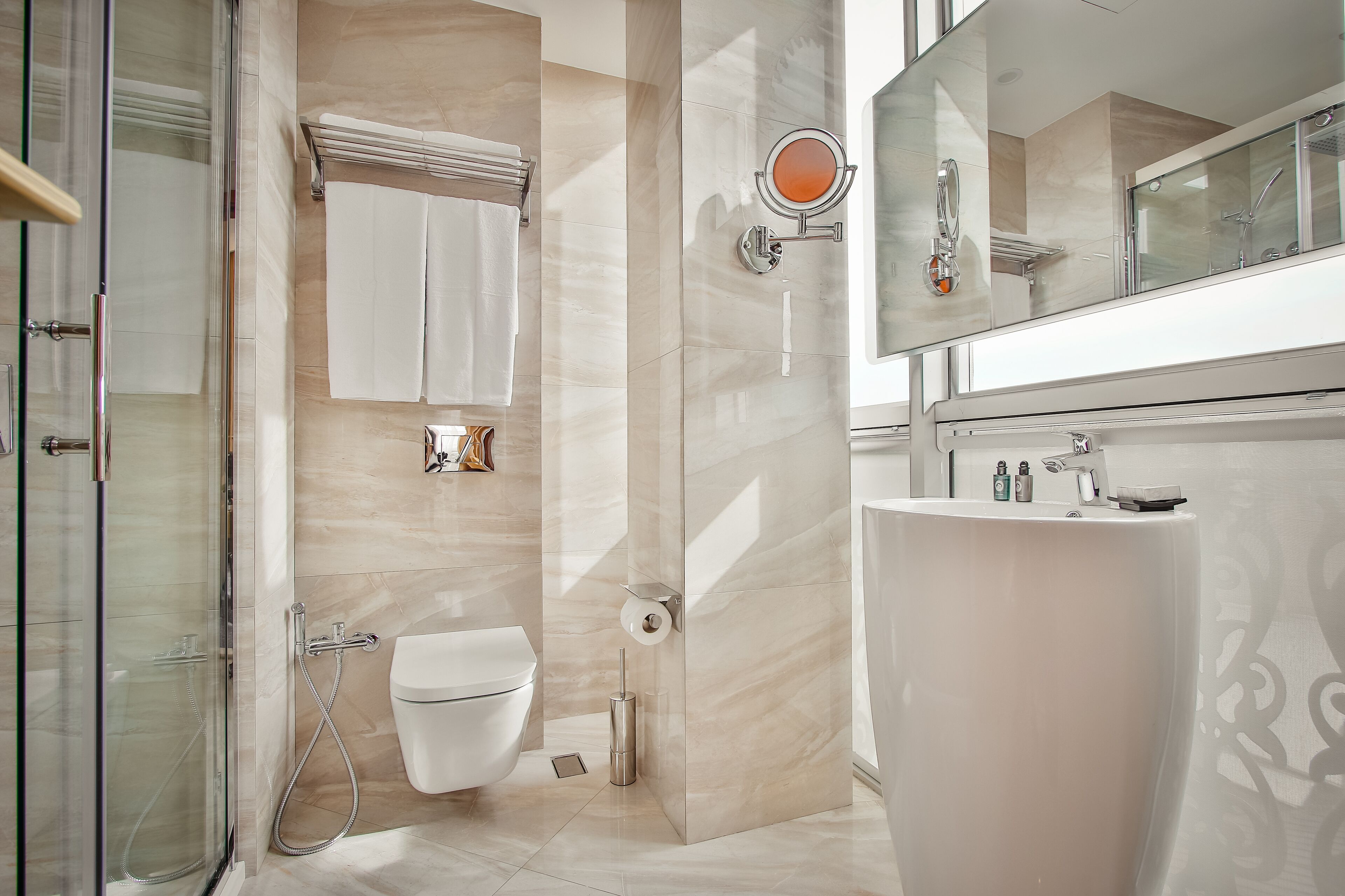 A modern bathroom with a glass shower enclosure, a toilet, and a sink with a mirror above it.