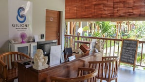A reception desk with wooden chairs, a computer, and a signboard for a hotel named Gilione. - Gili One Hotel & Resort (Gili Trawangan)