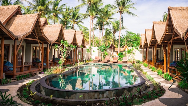 A resort with thatched-roof bungalows, a central pool, and palm trees. - Gili One Hotel & Resort (Gili Trawangan)
