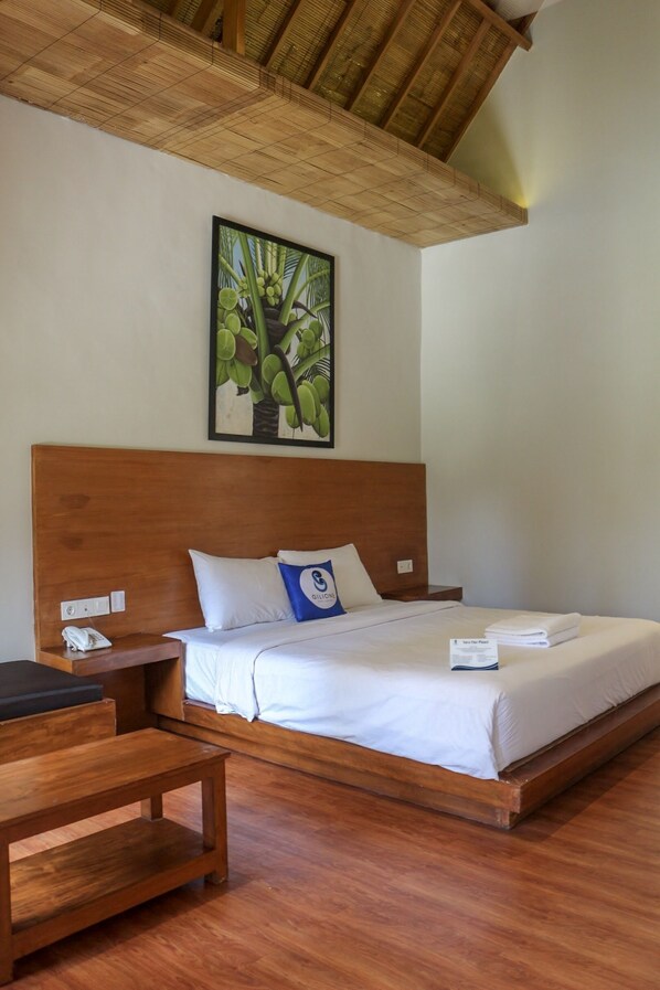 A hotel room with a wooden bed, a nightstand, a wooden table, and a ceiling with a woven design. - Gili One Hotel & Resort (Gili Trawangan)