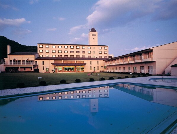 A hotel with a swimming pool, a large building with a tower, and a well-maintained lawn. - Akiu Resort Hotel Crescent (Sendai)