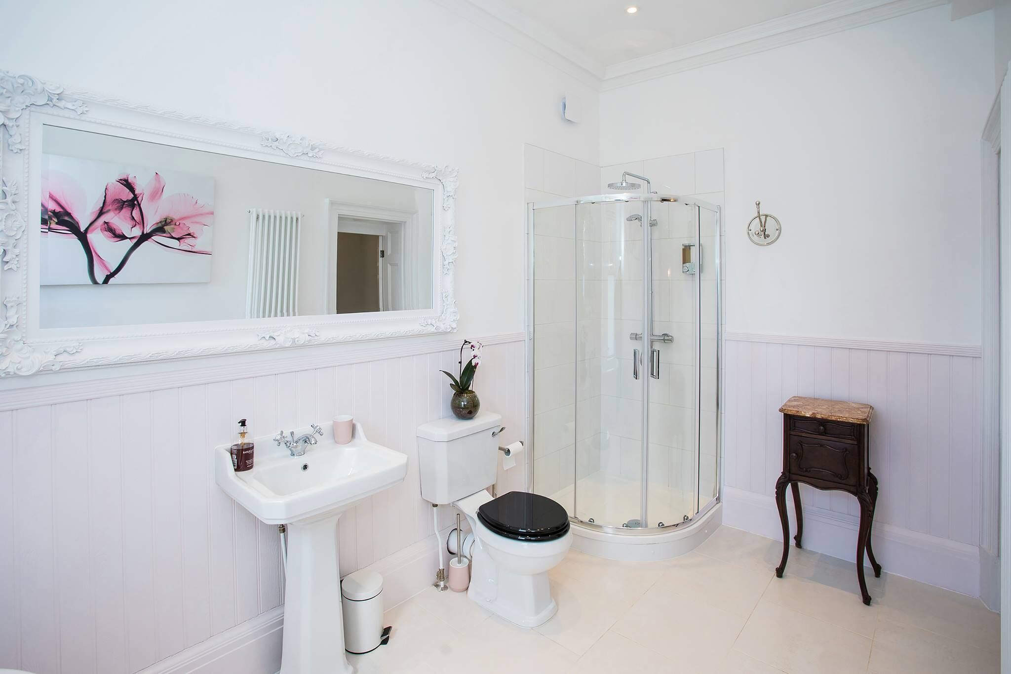 Un baño con lavamanos, inodoro y ducha blancos.