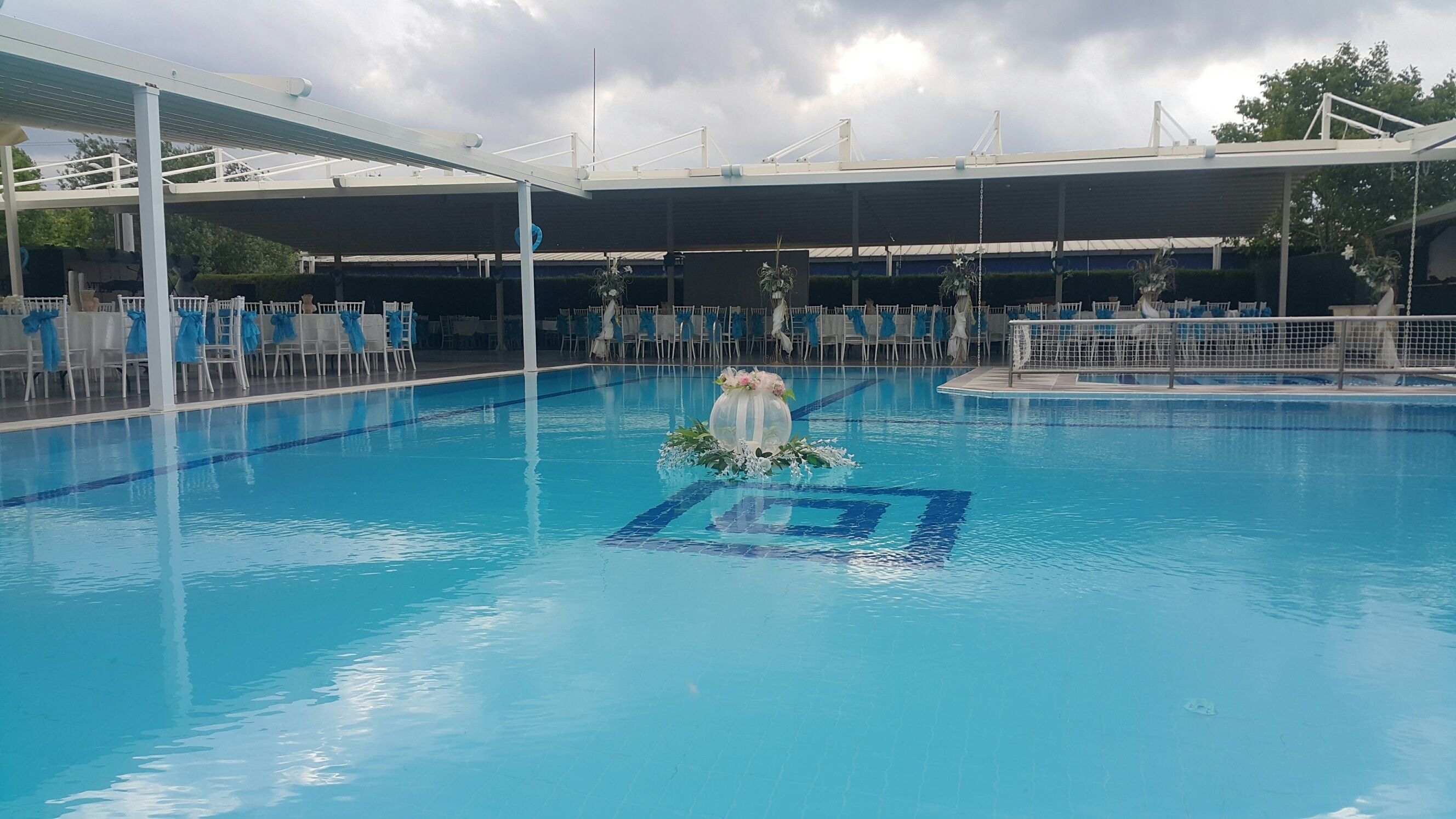 Een buitenzwembad, parasols bij het zwembad en ligstoelen