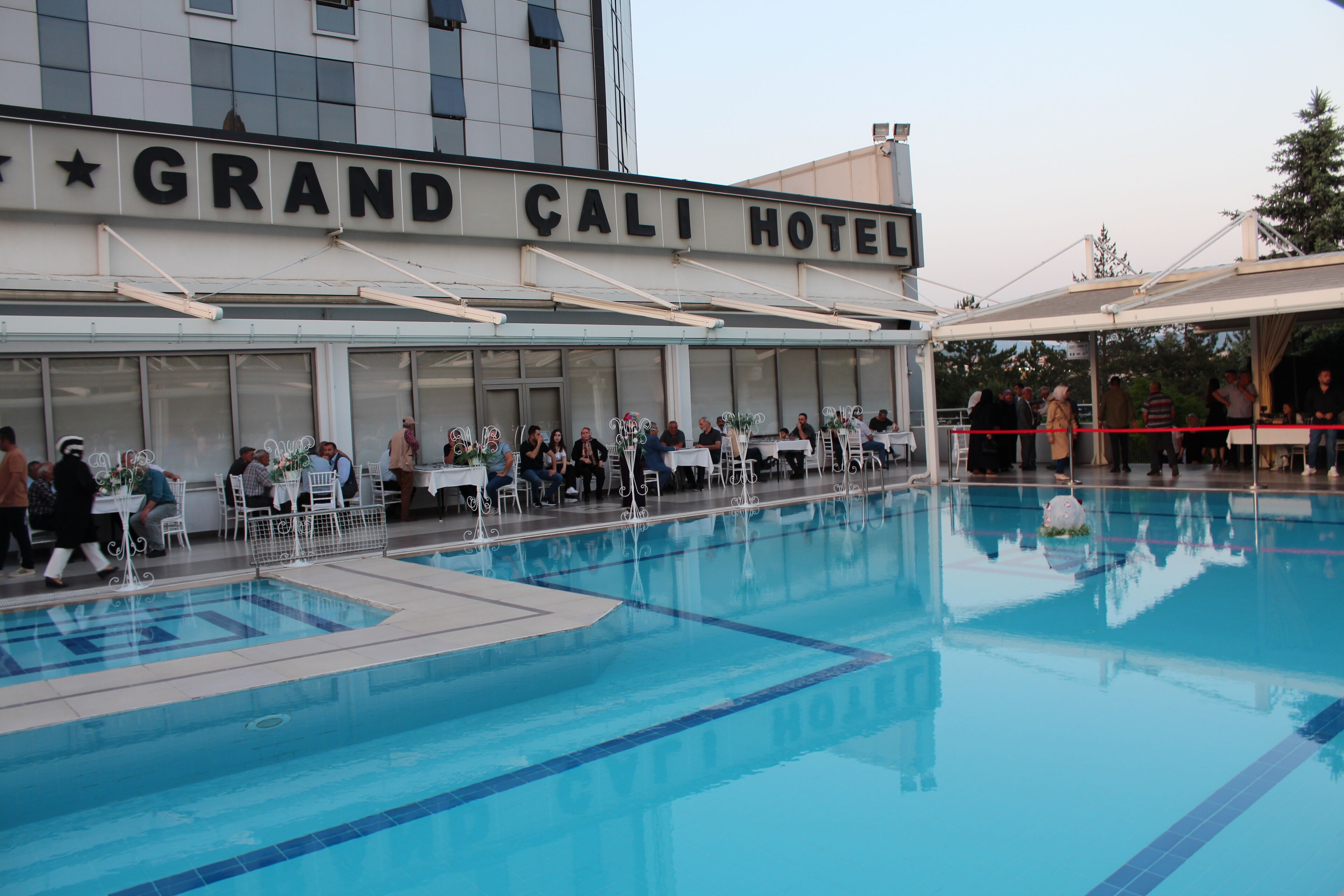 The Grand Cali Hotel with a swimming pool, outdoor seating area, and a covered patio.