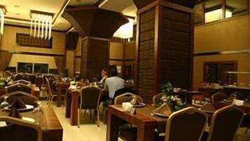 A spacious dining area with multiple tables and chairs, wooden paneling on the walls, and a warm ambient lighting.