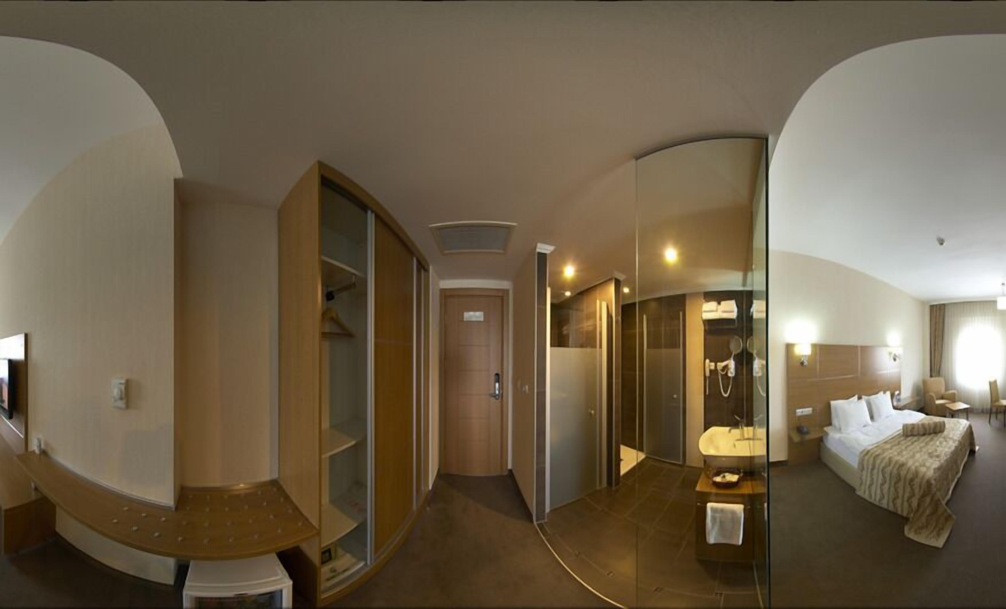 A hotel room with a bed, a small bathroom, a desk, and a closet.