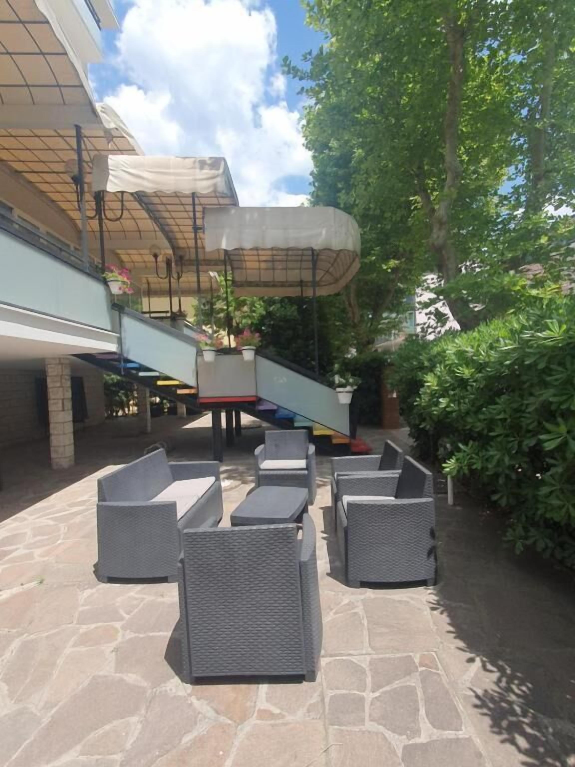 An outdoor patio area with wicker furniture, a covered seating area, and a stone floor.