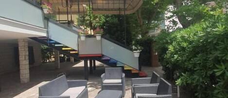 An outdoor patio area with wicker furniture, a covered seating area, and a stone floor.
