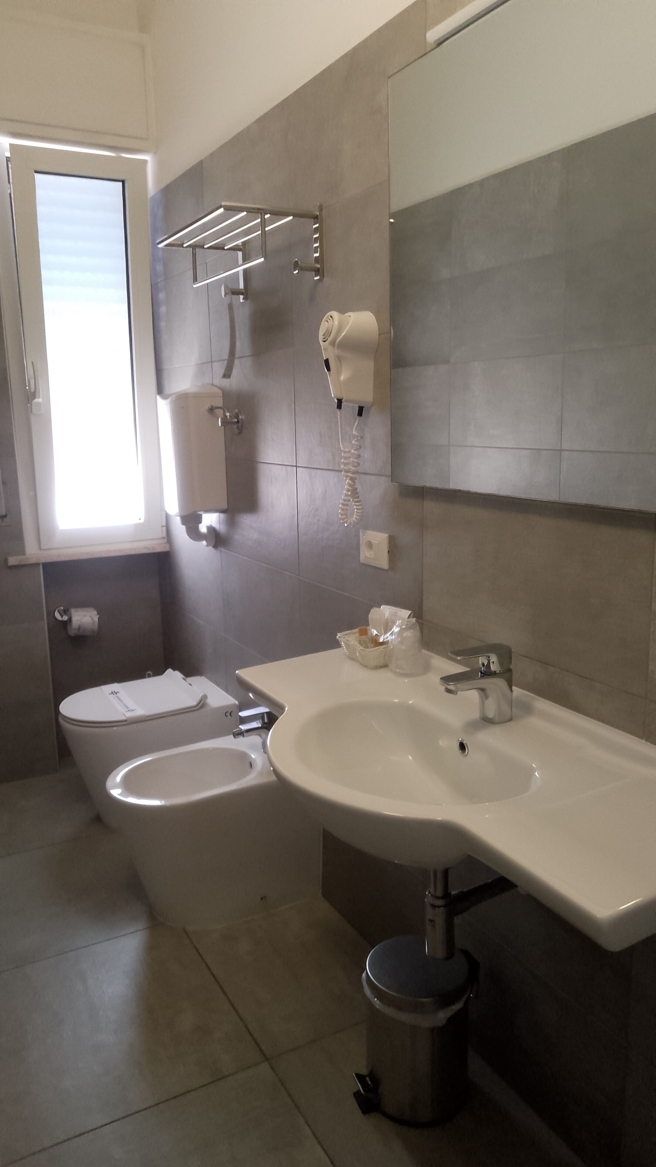 A bathroom with a toilet, bidet, sink, and a towel rack.