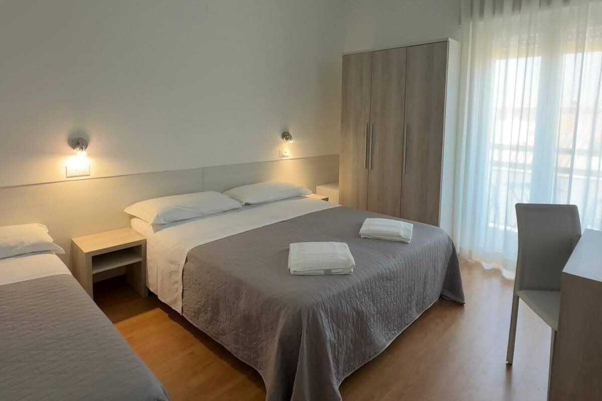 A hotel room with two beds, a desk, and a chair.