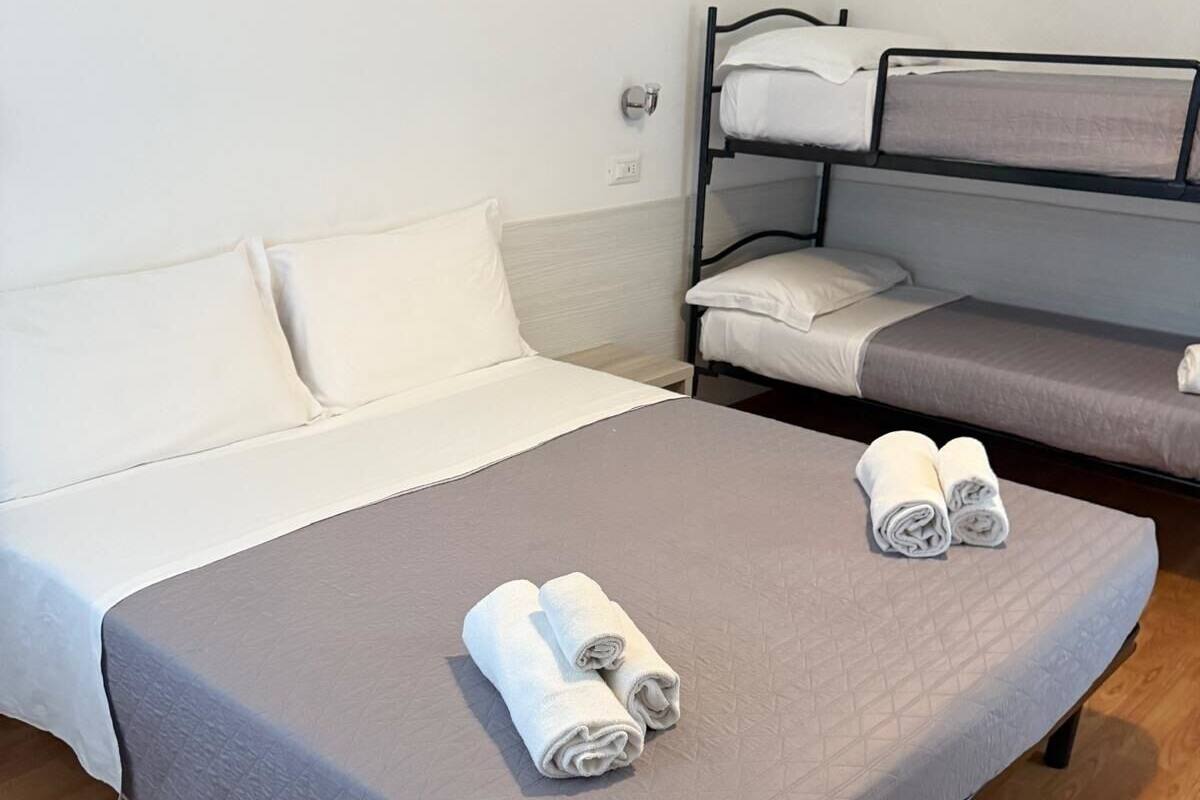 A hotel room with a single bed, a bunk bed, and a small table.
