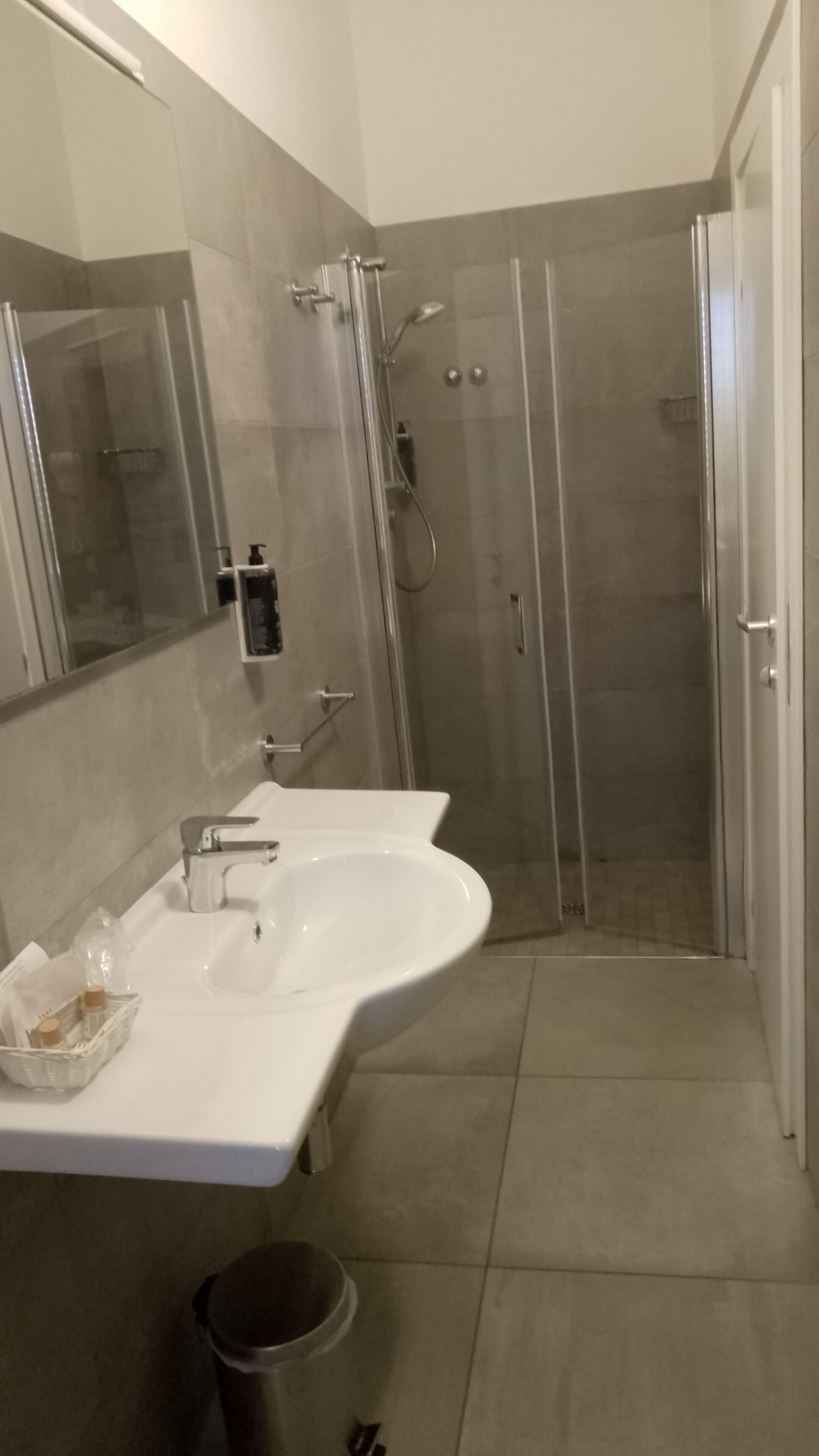 A bathroom with a double sink, a glass shower enclosure, and a mirror.