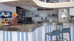 A modern bar area with striped blue and white walls, a curved counter, and two blue bar stools.