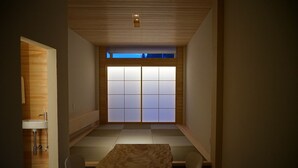 A traditional Japanese-style room with tatami flooring, a low table, and a sliding shoji screen door.