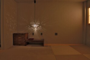 A dimly lit room with a wooden chest of drawers and a bench.