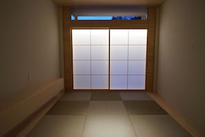 Une pièce avec un sol recouvert de tatamis, une porte coulissante de style shoji et un plafond en bois.