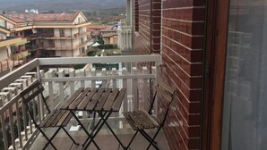 Un balcon donnant sur un quartier résidentiel, avec des montagnes en arrière-plan.