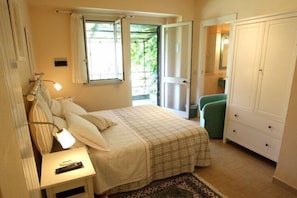 Une chambre à coucher avec un lit, une table de chevet, une lampe et une vue sur l’extérieur.