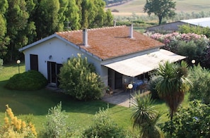 Une maison de plain-pied avec un toit en tuiles, une véranda et un jardin bien entretenu.