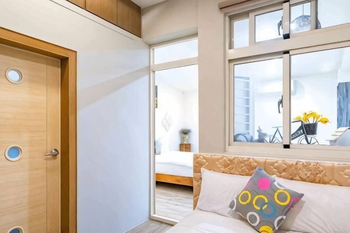 Ein Schlafzimmer mit Bett, Fenster, Tür und Blick nach draußen.